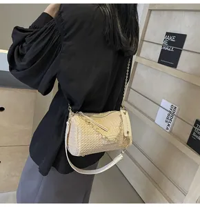 Detail of straw woven baguette bag showing raffia texture and silver chain strap