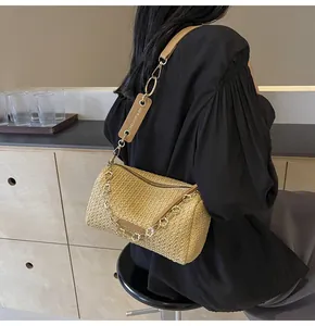 Detail of hand-woven cylindrical straw shoulder bag with leather strap and golden chain link