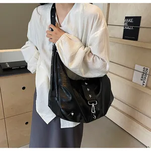 Detail of black oversized hobo bag featuring silver star rivets and soft leather texture