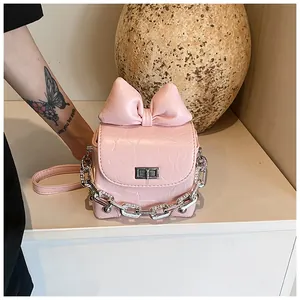 Detail van roze strik en zilveren ketting met strass-steentjes op een crossbody tasje