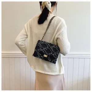 Détail du sac bandoulière en tweed noir avec chaîne dorée et texture denim matelassé