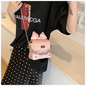 Detail van roze mini-crossbodytas met metalen ketting, grote strik en draaisluiting