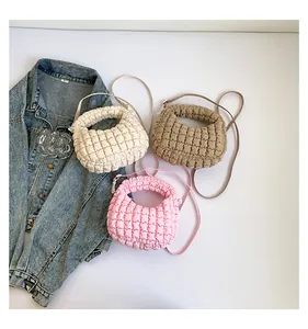 Détail de trois sacs matelassés en blanc, kaki et rose posés sur une surface blanche unie