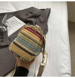 Detail of colorful rainbow straw bucket bag with gold chain and white leather strap