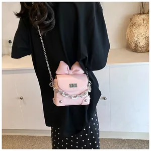 Detail van een roze mini-schoudertas met grote strik en zilveren sluiting bij een model