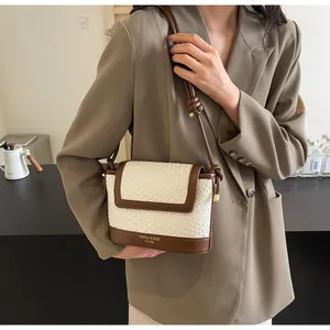 Détails de la texture tissée et du logo doré sur ce sac à bandoulière chic
