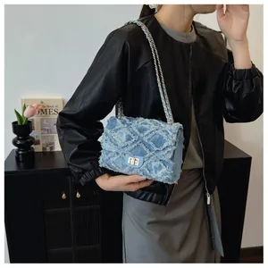 Détail du sac en jean à chaîne avec surpiqûres matelassées et boucle dorée