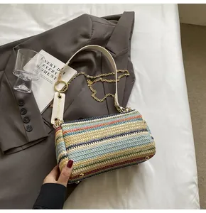 Detail of colorful woven cylinder bag with gold chain and white leather strap
