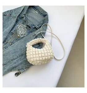 Détail du sac nuage matelassé blanc cassé avec veste en jean sur un fond moderne chic