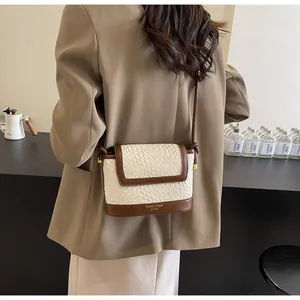 Détail de la texture tressée et du logo sur le sac bandoulière beige et marron