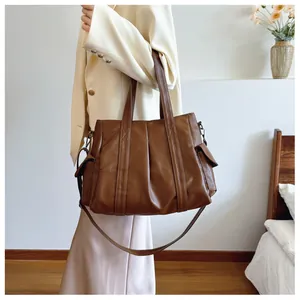 Detailansicht einer großen braunen Tote Bag mit Seitentaschen an einem Model im Raum