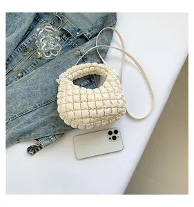 Vue détaillée d'un sac nuage crème avec texture matelassée à côté d'un smartphone