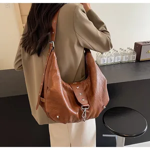Detail of brown vintage leather tote bag featuring star rivets and adjustable wide strap