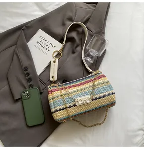 Detail of multi-color striped straw cylinder bag with gold chain on grey suit jacket