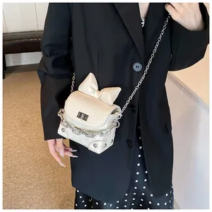 Detail van een gebroken witte crossbodytas met strik en zilverkleurige ketting