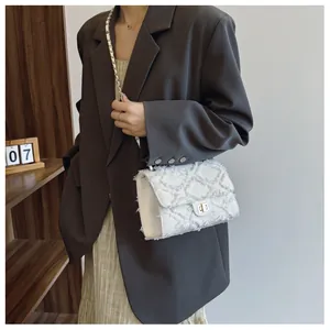 Gros plan sur la texture tweed blanc et le fermoir tournant doré du sac à bandoulière