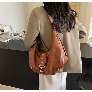 Detailed close-up of brown vintage leather hobo bag featuring silver star studs and hook