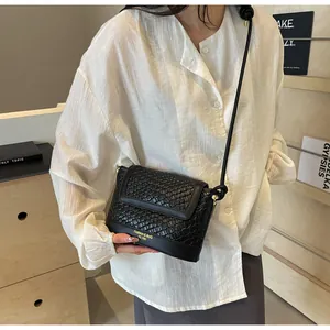 Gros plan sur la texture en cuir tressé noir et la boucle en métal du sac bandoulière