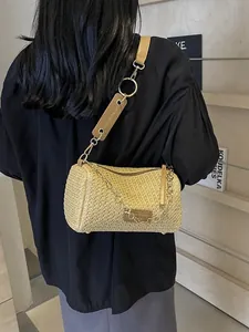 Straw cylinder crossbody bag with rainbow chain and leather strap in soft home setting