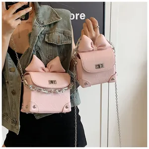 Detail van roze tas met strik, zilveren ketting en klinknagels op mini crossbody tas