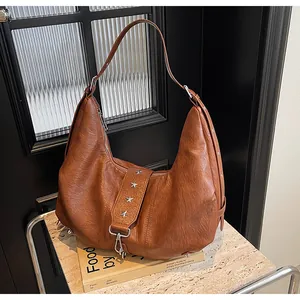 Close-up of vintage brown crescent tote with silver star rivets and retro wrinkled texture