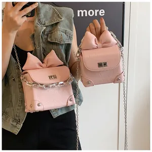 Detail van roze mini boxtas met strik, metalen sluiting en een zilveren kettingriem