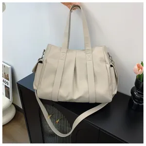 Detail der beige plissierten Tragetasche mit verstellbarem Gurt und Vintage-Beschlägen