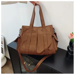 Detail einer großen braunen Shopper-Tasche mit seitlichen Klapptaschen und Faltenoptik