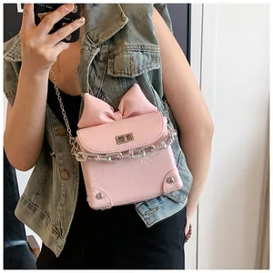 Detail van roze geplooide mini crossbody tas met een grote strik en zilveren ketting