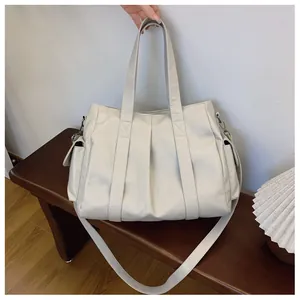 Detail einer großen cremefarbenen Shopper-Tasche aus strukturiertem Leder auf Holz