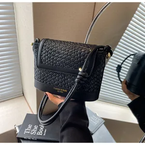 Détail du sac bandoulière en cuir tressé noir avec texte doré et texture fine