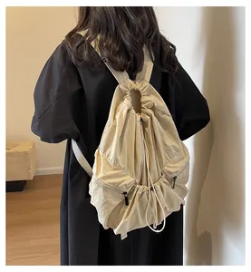 Back view of a beige nylon backpack with drawstring closure and minimalist style