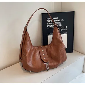 Detail of caramel brown hobo bag with star-shaped rivets and soft pleated leather texture