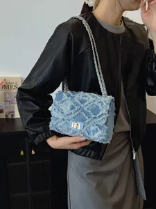 Sac bandoulière en denim matelassé avec chaîne dorée porté par un mannequin en cuir
