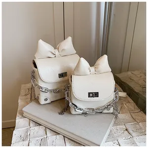 Detailweergave van grote en kleine gebroken witte handtassen met strikken, kettingen en PU-leer
