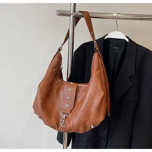 Detail of vintage brown leather hobo bag with silver star studs and metal hooks