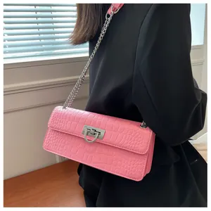 Close-up of pink croc-embossed small square bag with silver D-ring buckle and metal chain strap