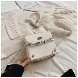 Detail van de crèmewitte mini-tas met een grote strik en zilveren kettingriem