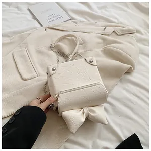 Detailweergave van de crèmewitte mini crossbody tas met getextureerd leer en grote strik