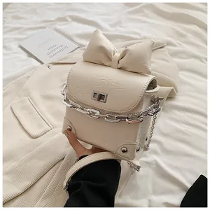 Detail van gebroken witte mini-tas met strik, geplooid leer en diamanten kettingriem