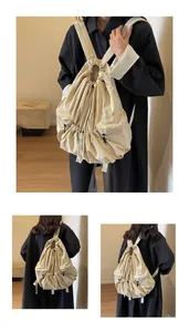 Detail view of beige nylon backpack with multi-pocket design and drawstring closure