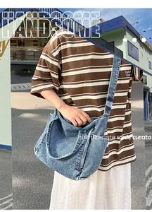 Detail of washed blue denim messenger bag showing textured fabric and wide shoulder strap