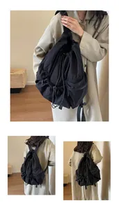 Detailed close-up of a black nylon drawstring backpack showing straps and side zipper pocket