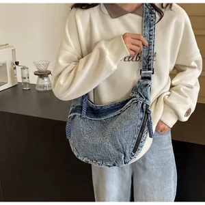 Détail du sac bandoulière croissant en jean délavé avec texture bleue vintage et bandoulière