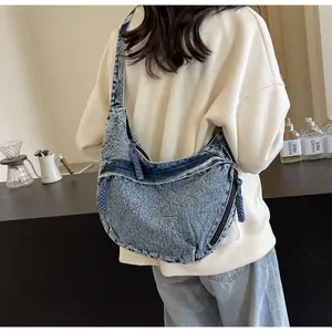 Détail montrant la texture du sac bandoulière en denim délavé avec fermeture éclair