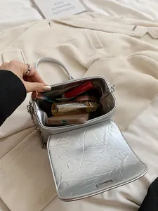 Zilveren crossbodytas met striktextuur, kettingriem en zicht op de binnenopslag