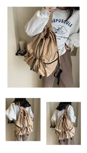 Detail of a khaki nylon drawstring backpack with black zippers and spacious side pockets