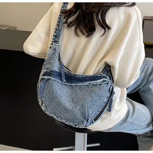 Détail du sac demi-lune en jean bleu clair avec tirette de fermeture tressée bleue