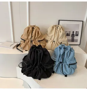Detail view of nylon drawstring backpacks in khaki, cream, black and sky blue colors