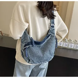 Détail macro du sac hobo en denim délavé montrant la texture et le tire-zip tressé
